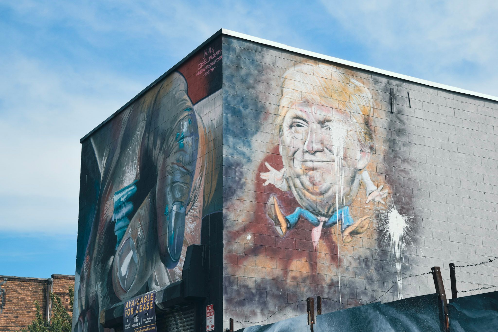 Edificio con murales en dos de sus paredes, uno con una caricatura de Donald Trump, bajo un cielo con nubes