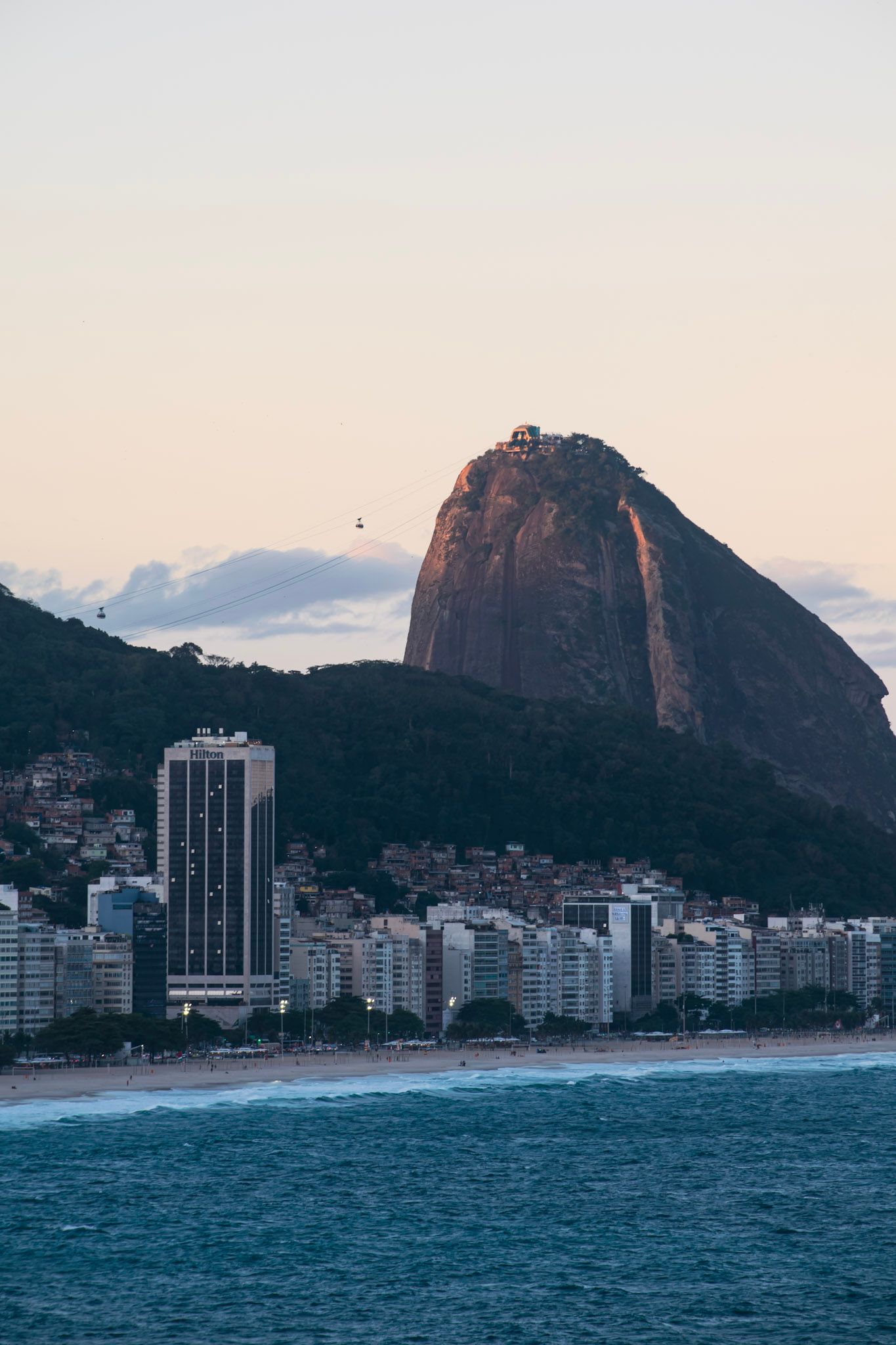 El Pan de Azúcar con el teleférico, sobre la línea de edificios de la playa y el mar, al atardecer