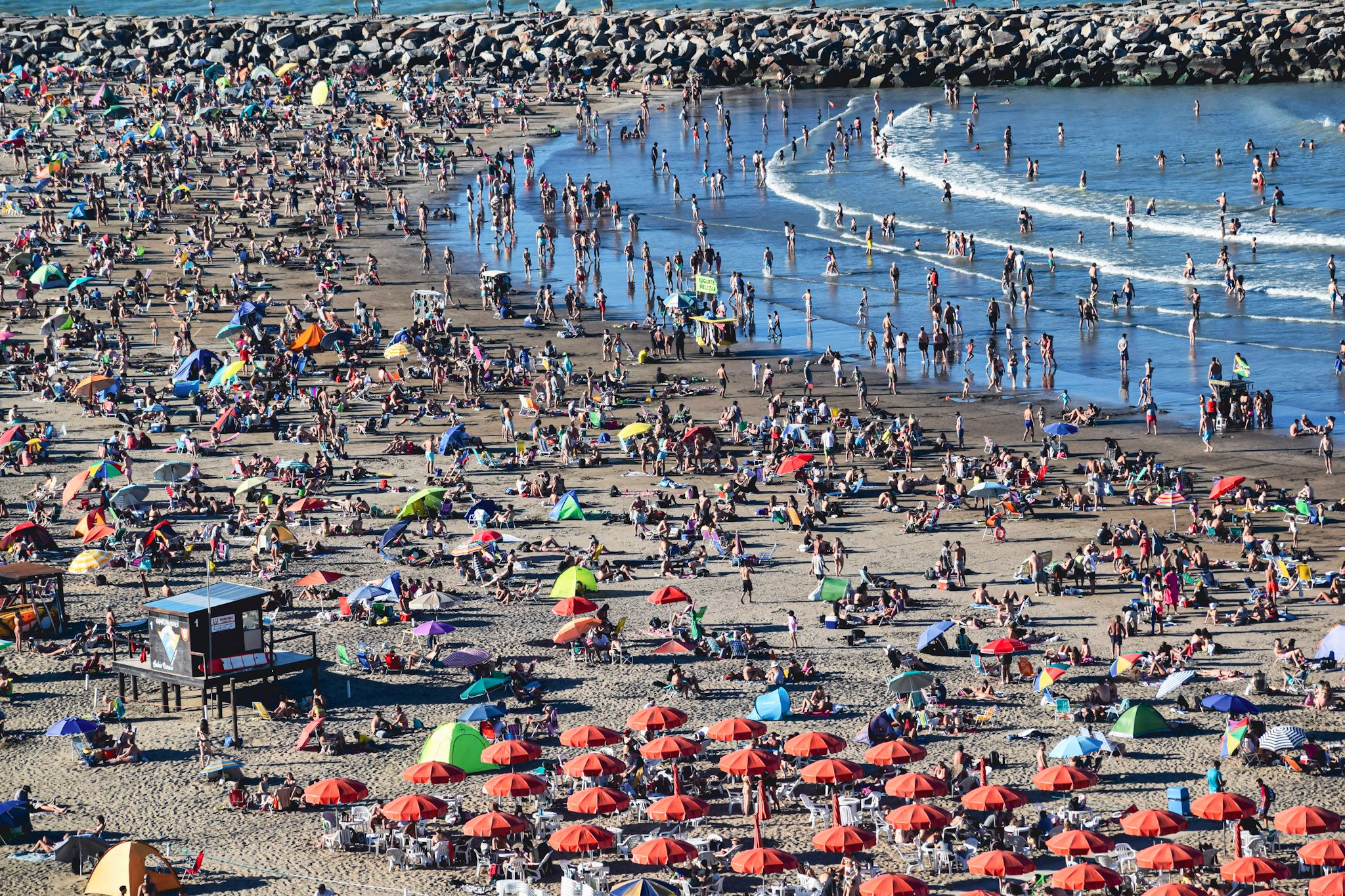 Playa repleta de gente vista desde arriba, con sombrillas de colores y el agua turquesa
