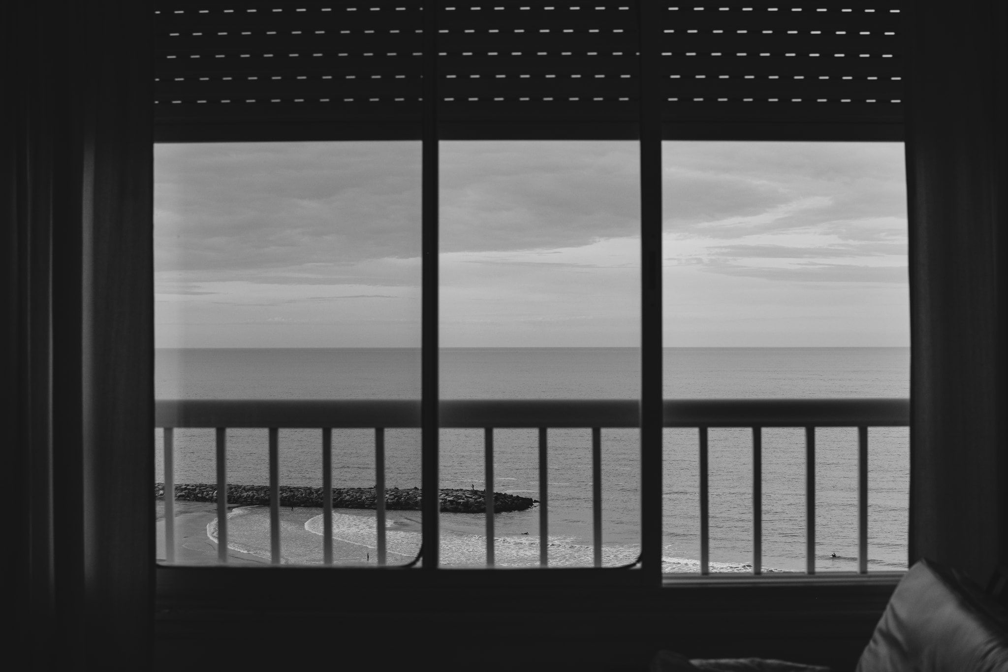 El mar visto a través de una ventana con baranda, en blanco y negro